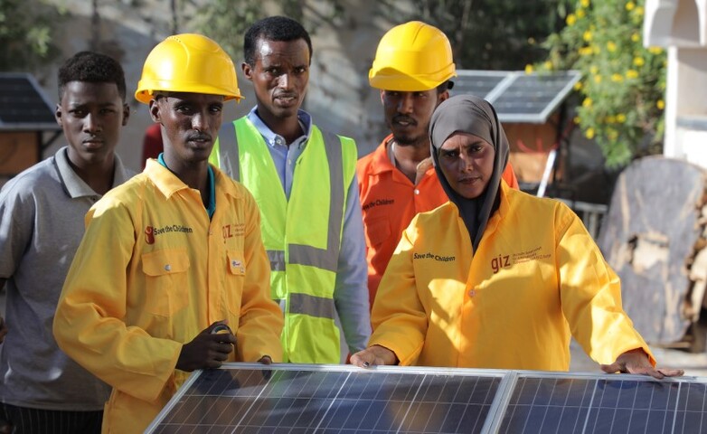 gizIMAGE-five-people-wear-protective-clothing-and-stand-behind-a-solar-panel_rdax_782x480s